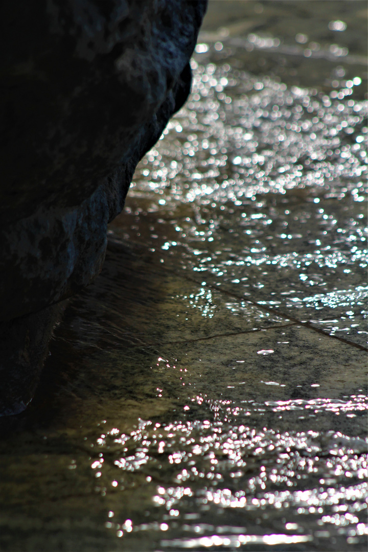 Wasser umspült den Stein , und die Sonne kokettiert mit dem Wasser