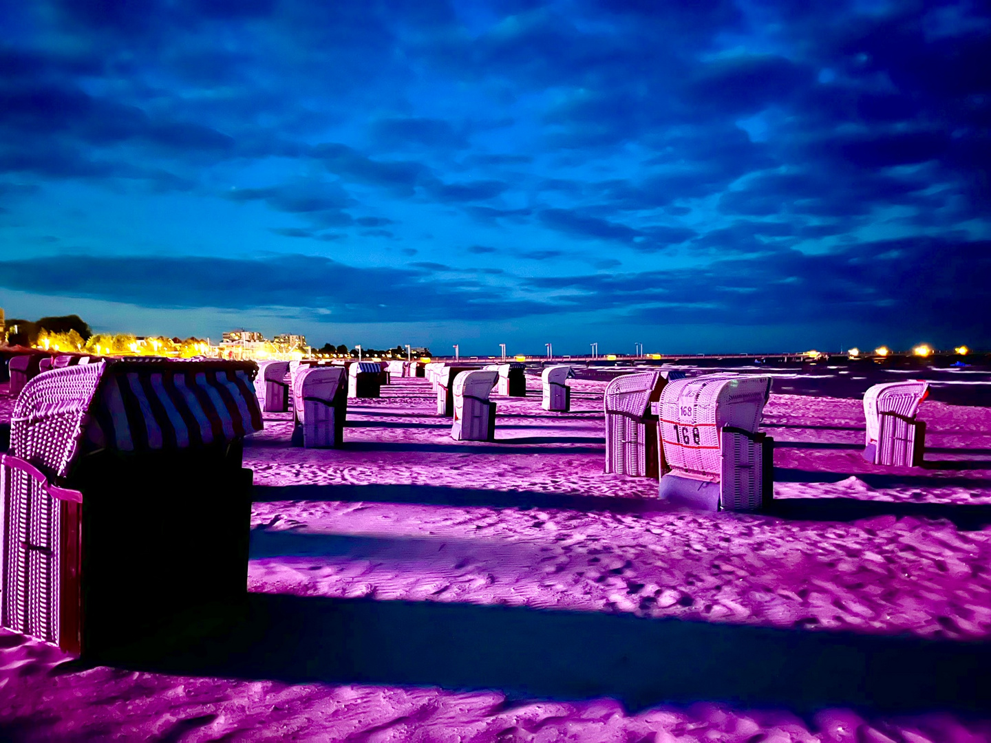 wenn sich bei Nacht das Licht vom Riesenrad über die Strandkörbe ergießt 