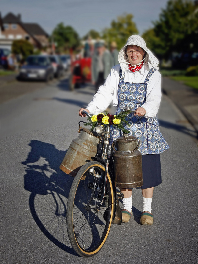 Westfälische Bäuerin mit Milchkannen am Fahrradlenker