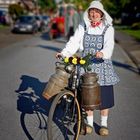 Westfälische Bäuerin mit Milchkannen am Fahrradlenker