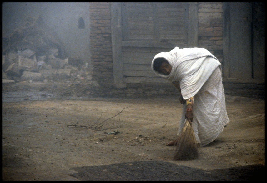 Wife von Bahadur cleaning the road vor ihr haus, easily to recognize an sein umhang