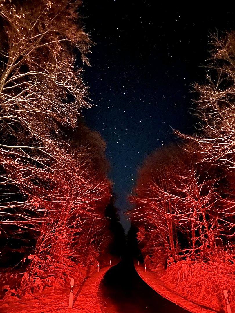 Winterliche Straße im Bremslicht mit Sternenhimmel 