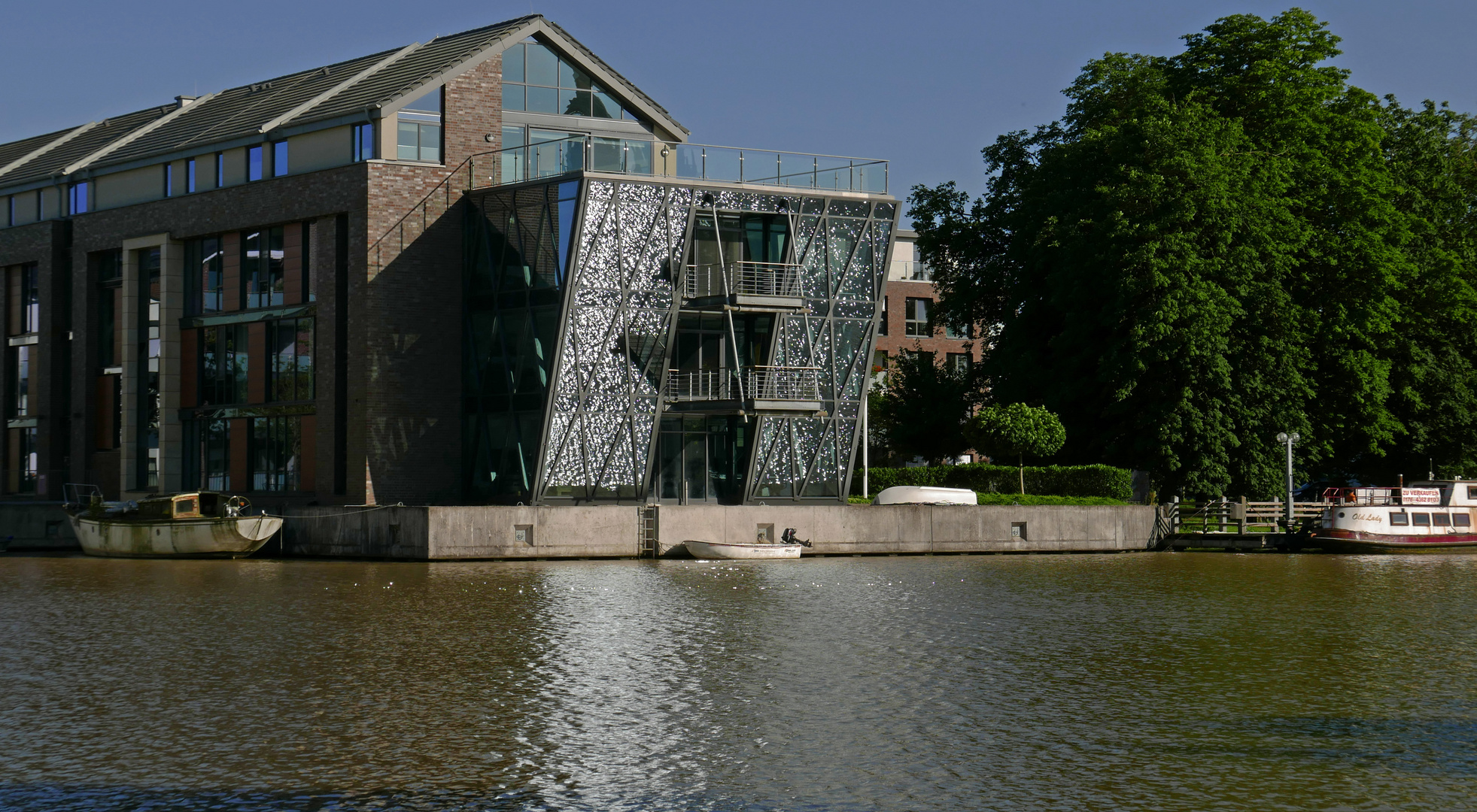 Wohnen am Wasser, das moderne Leer: riesige Fensterfronten mit Spiegelung vom Wasser aufs Glas.