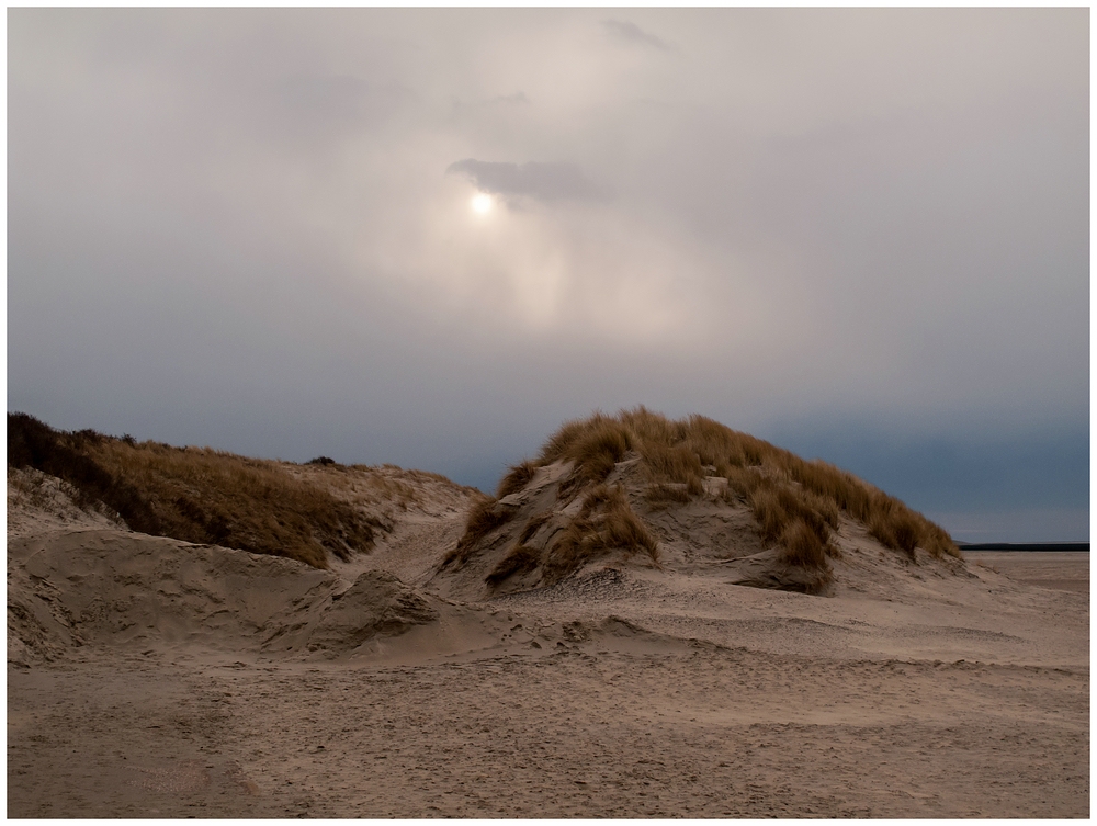 Wolkenverhangene Sonne über den Dünen