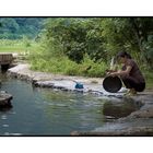 Woman washing dishes in a stream