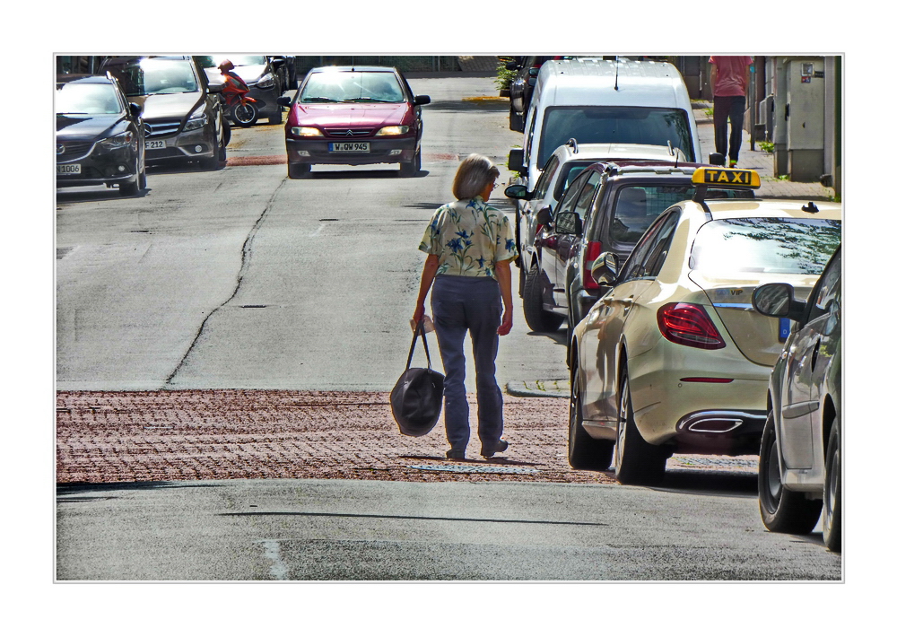 Woman with a very large handbag walks across the street