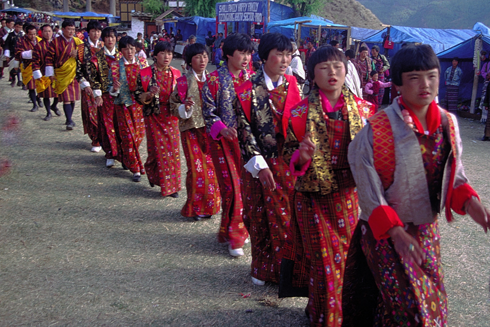 Women in traditional kira enter the tsechu