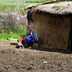 young mother with kids in front of hut