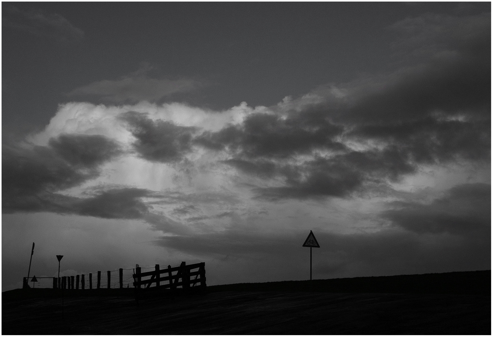 Zaun, Schilder und Wolken