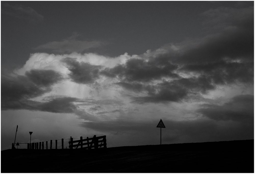 Zaun, Schilder und Wolken