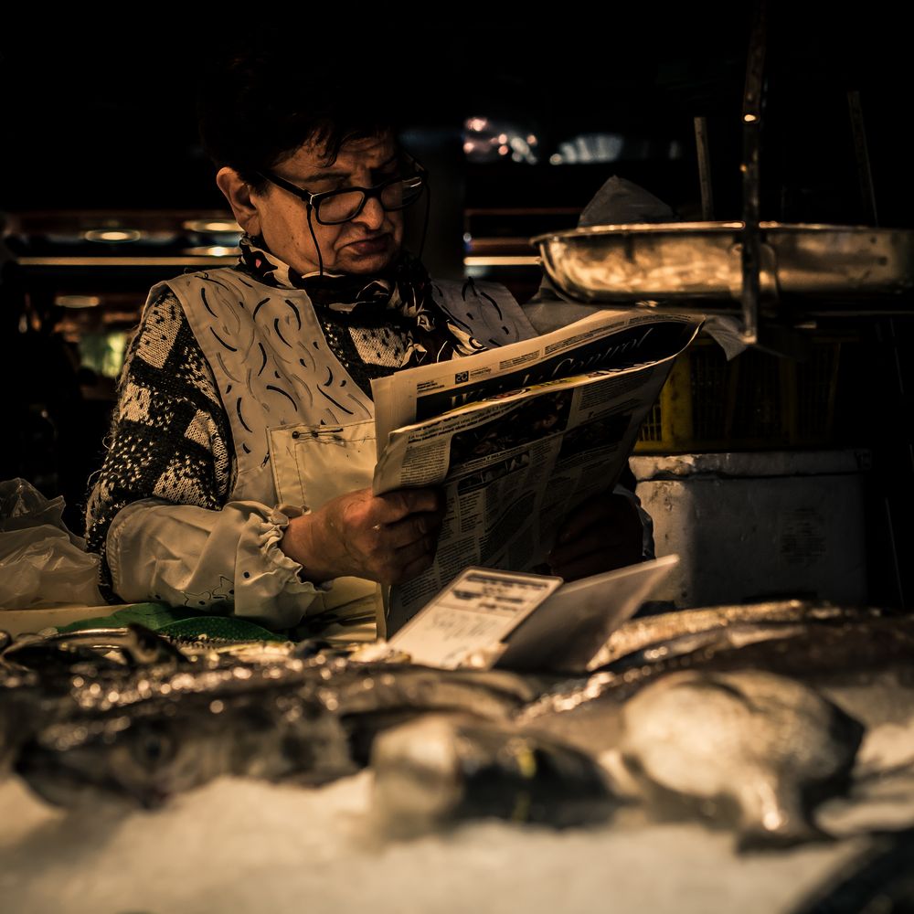 Zeitunglesende Fischverkäuferin