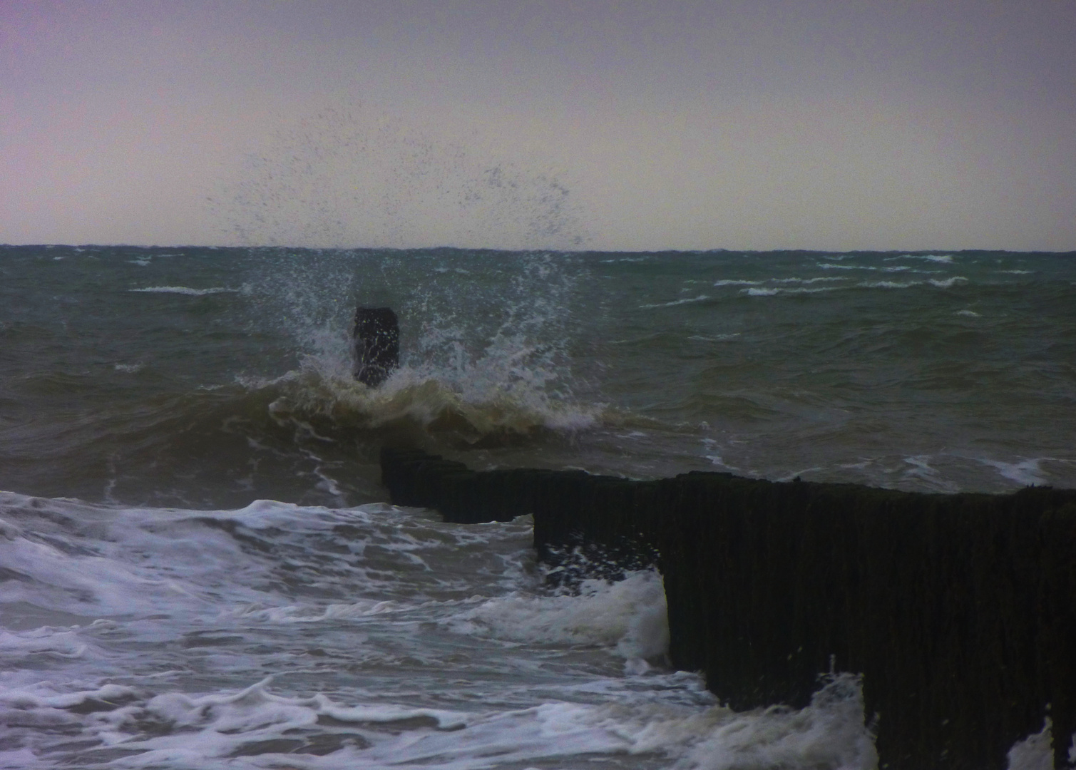 zerberstende Welle am Ende eines Wellenbrechers bei Sturm